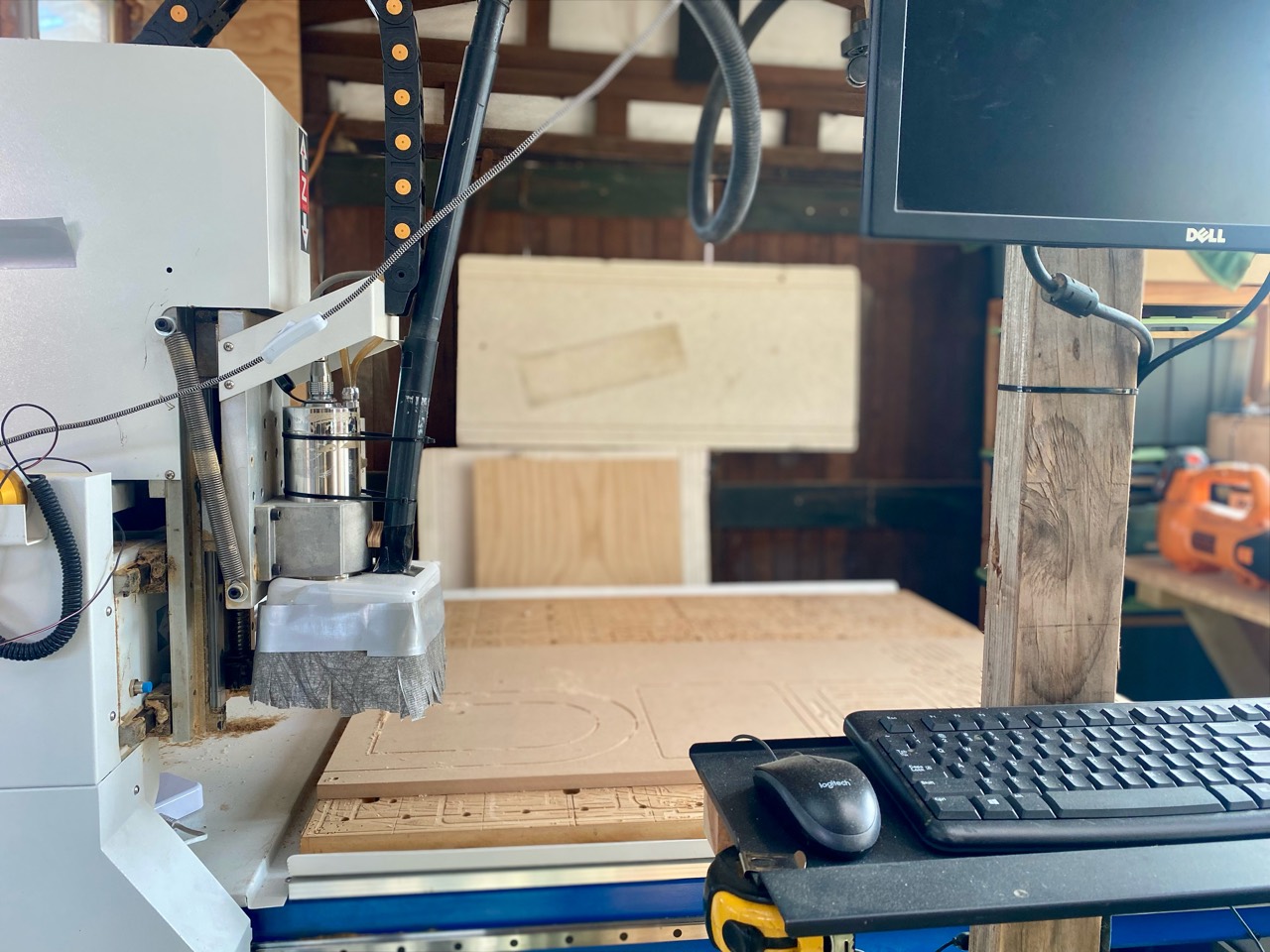 CNC router, timber stock, keyboard, and workshop monitor.