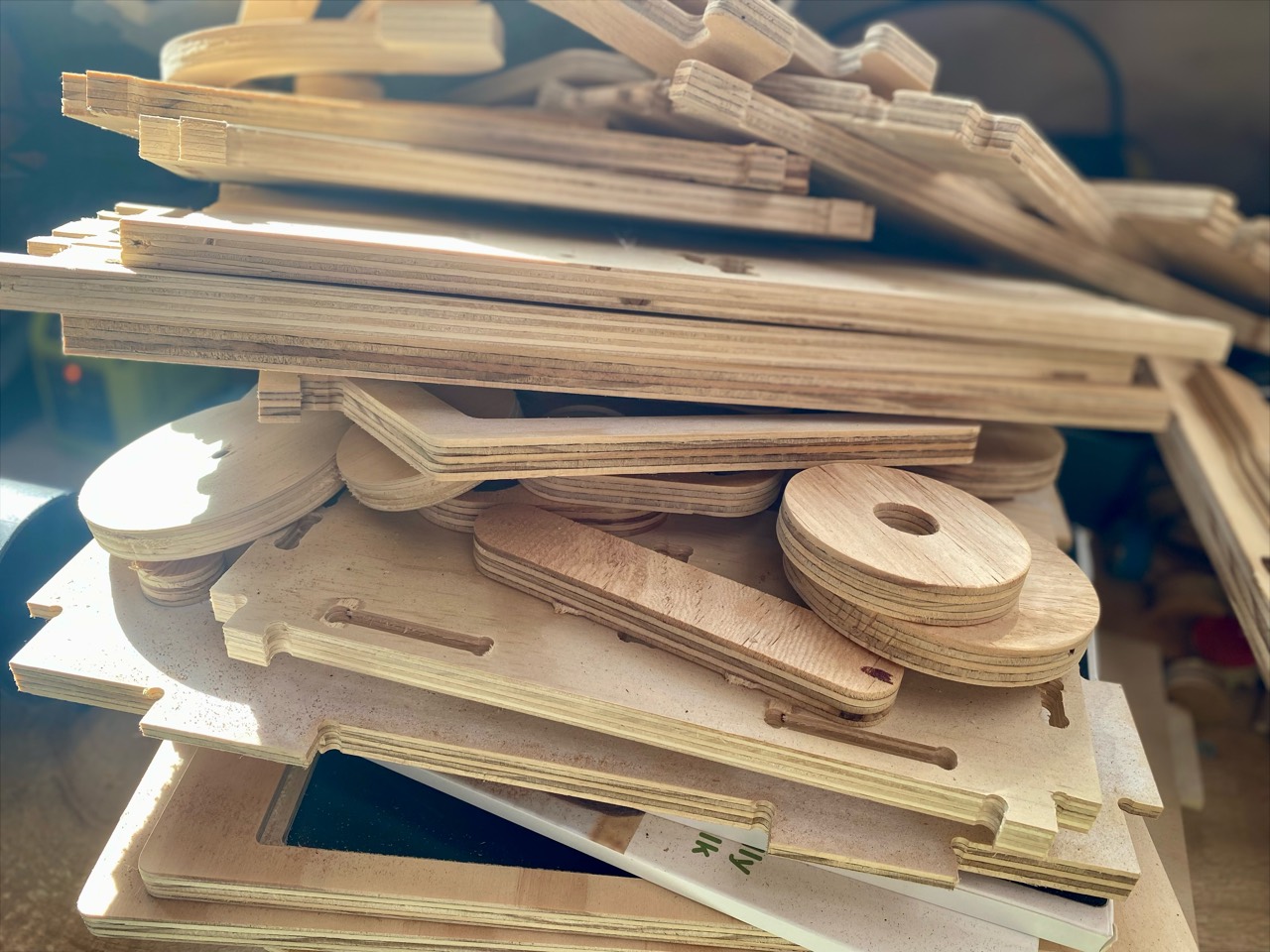 A pile of routed plywood shapes and offcuts.