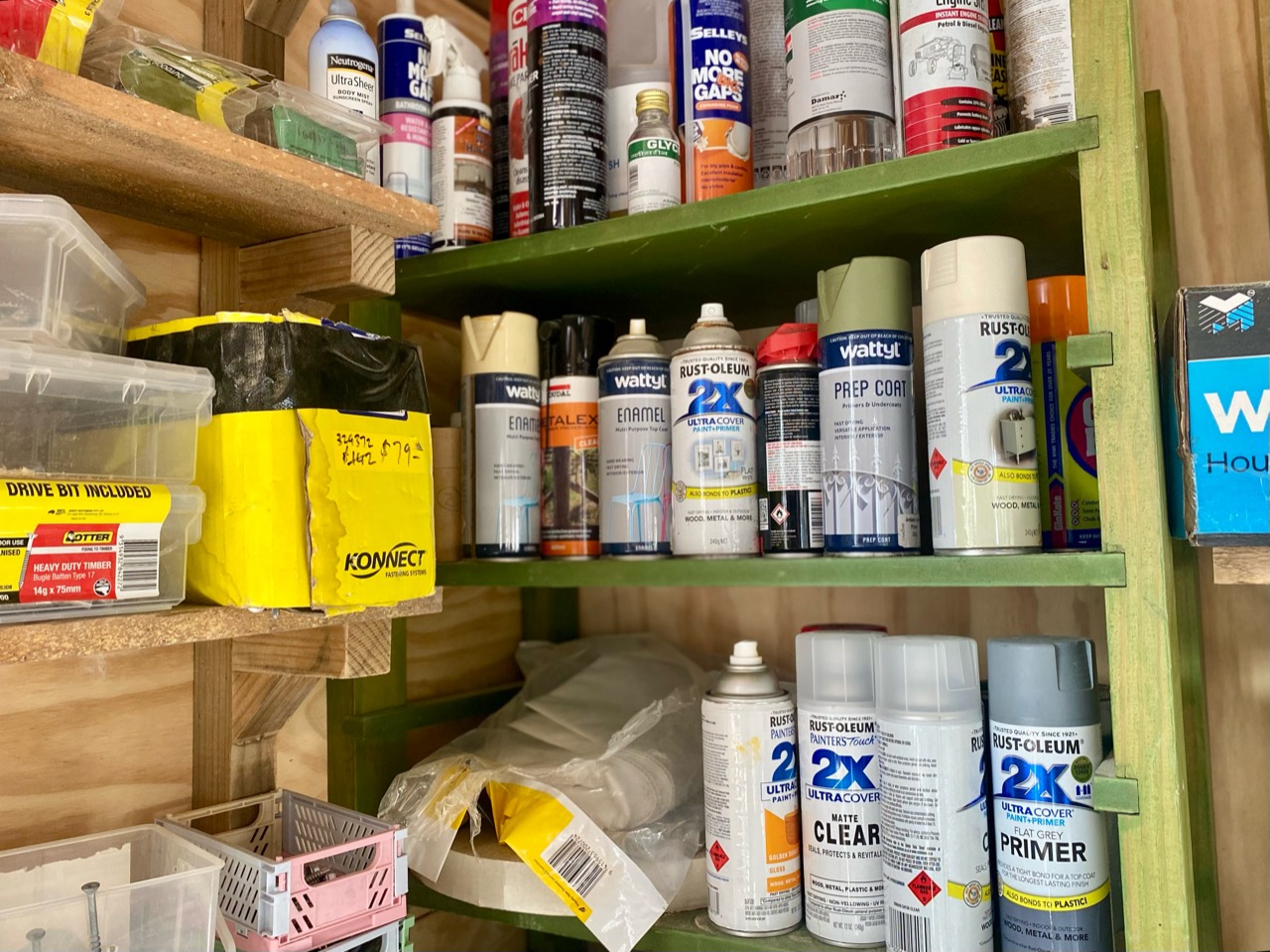 Paint, finishes, fixings, and material supplies stored on workshop shelves.