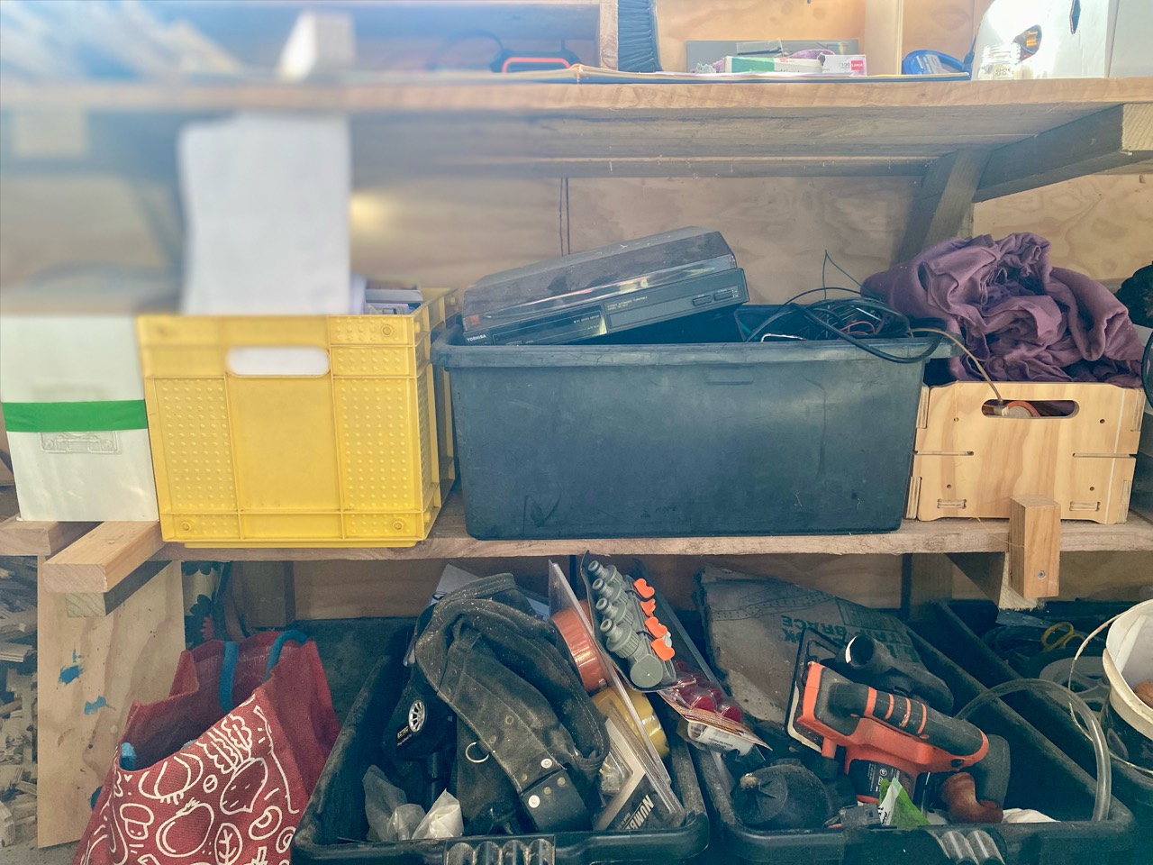 Crates, tools, cables, and salvaged equipment kept under a workshop bench.